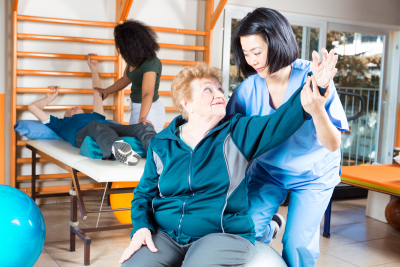 young caregiver helping her senior patient exercise