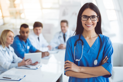 nurse wearing stethoscope smiling with her colleagues behind